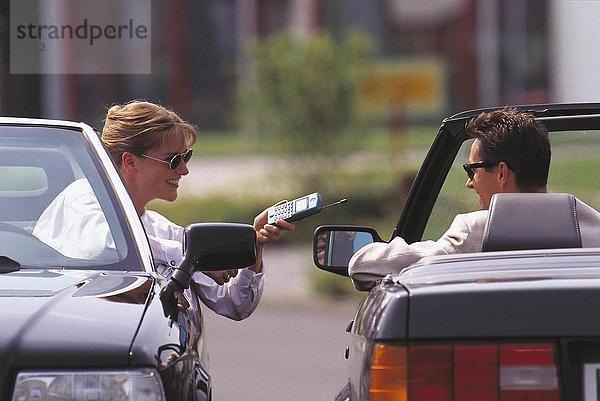 Frau hält ein schnurloses Telefon mit einem Mann in einem Auto sitzt
