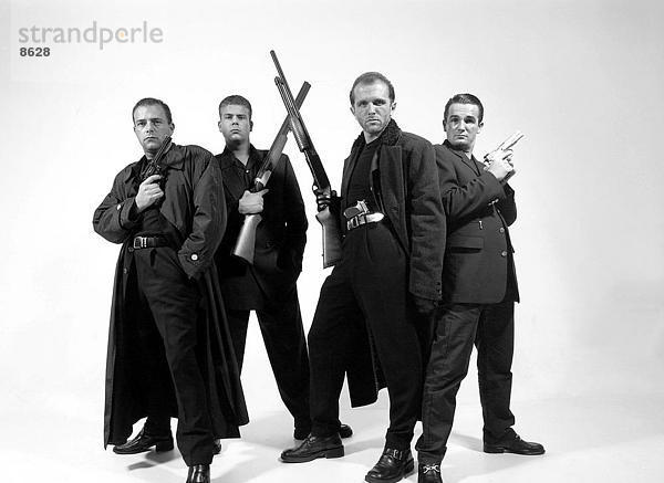 Vier Männer halten Gewehre und Pistolen