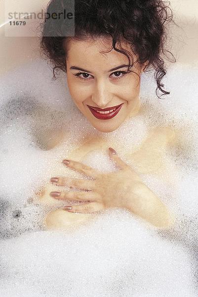 Portrait einer jungen Frau sitzen in einer Badewanne und lächelnd