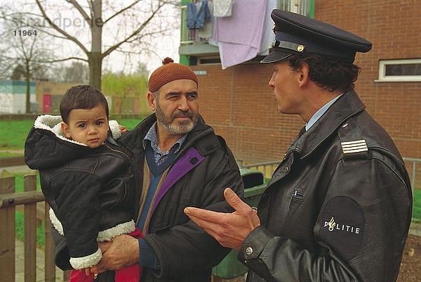 Polizist Gespräch mit Mann mit seinem Kind  Niederlande