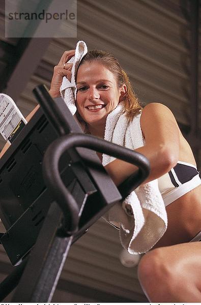 Portrait einer jungen Frau Ausübung und lächelnd in Fitness-Studio
