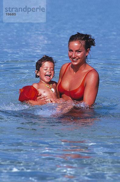 Mutter und Tochter lächelnd in Wasser