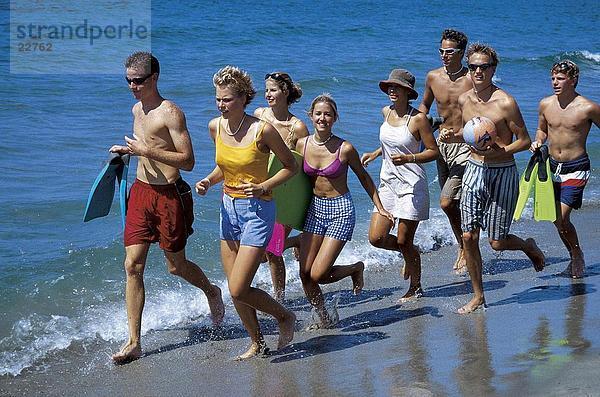 Jungen und Mädchen im Teenageralter ausgeführt am Strand