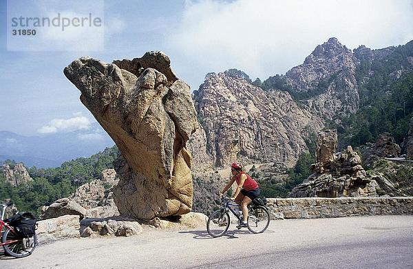 Frau Mountainbiken am Straßenrand  Les Calanches  Korsika  Frankreich