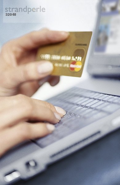Frau hält eine Kreditkarte und benutze ein laptop