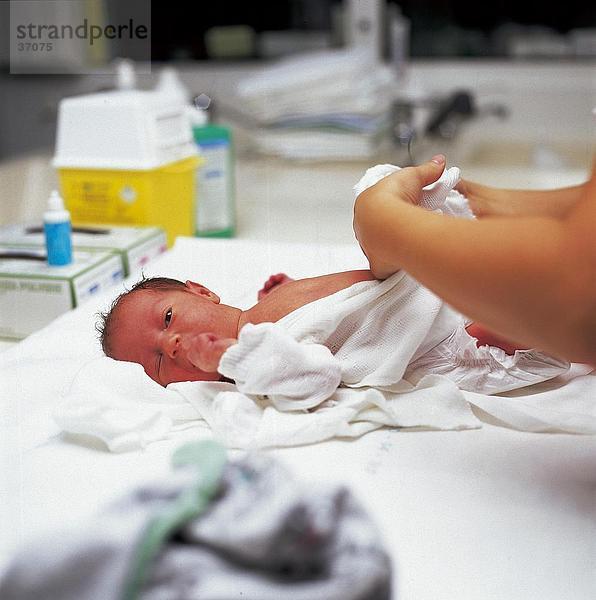 Krankenschwester Pflege für ein Neugeborenes Baby auf einem Krankenhausbett