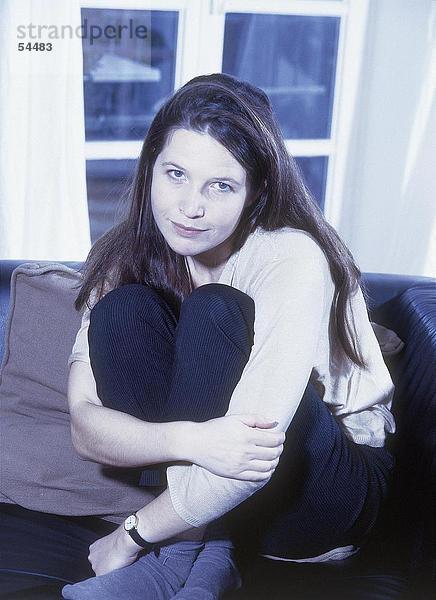 Portrait einer jungen Frau grinsend auf sofa