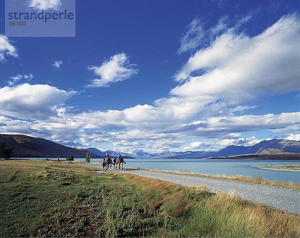 Zwei Menschen Reitpferde an der Küste  Lake Tekapo  Südinsel  Neuseeland