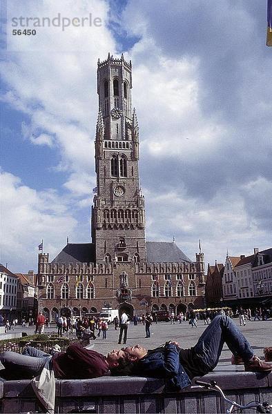 Zwei Männer schlafen auf Mauer vor Uhrturm  Bruges  Belgien
