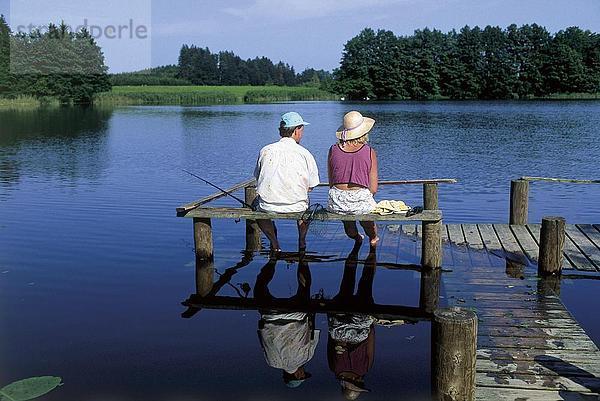 Rückansicht eines Paares sitzen auf eine Pier und Fischerei