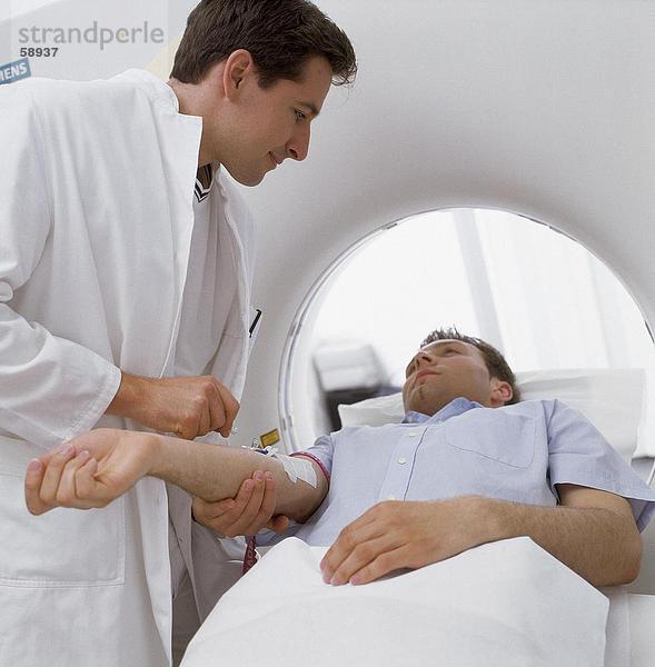Männlichen Arzt geben Injektion Patienten auf MRI Scannerglas