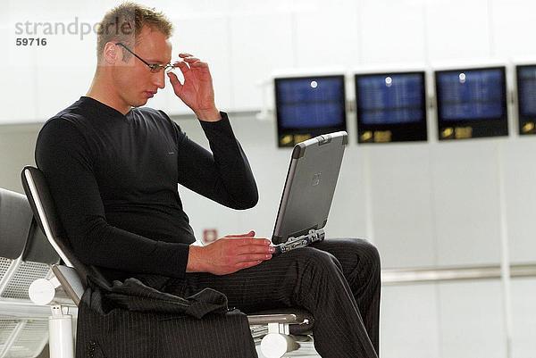 Seitenansicht Geschäftsmann mit Laptop im Wartezimmer am Flughafen