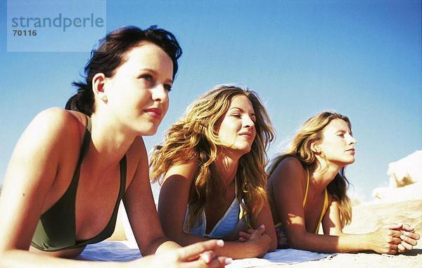 Drei junge Frauen am Strand sonnen