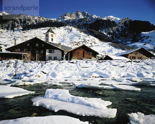 Berg Winter Wohnhaus Gebäude fließen Fluss Kirche Alpen Kanton Graubünden Bergpanorama