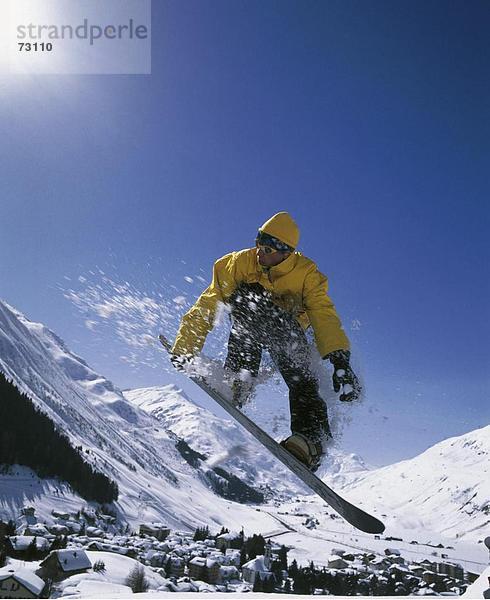 Europa Mann Snowboard Sport Mantel springen Dorf gelb Andermatt Kanton Uri Schweiz Wintersport