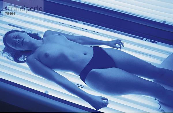 10637919  Schönheit  Strahlentherapie  bräunen  Frau  halb nackt  halb bedeckt  Lüge  Neonröhren  take it easy  entspannen  Solarium  Sonne