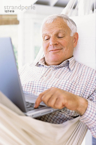 Großvater mit Laptop in der Hängematte