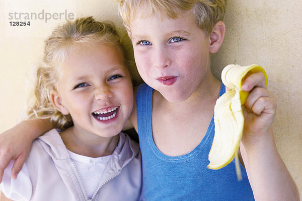 Junge umarmt Schwester und isst Banane