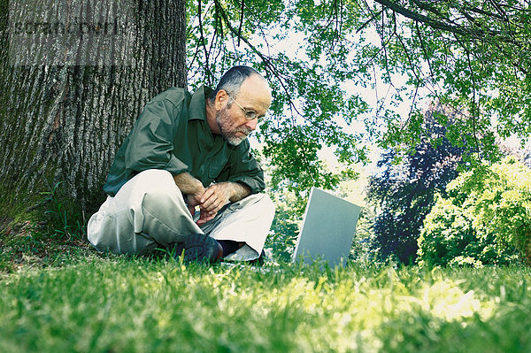 Mann schaut auf Laptop im Park