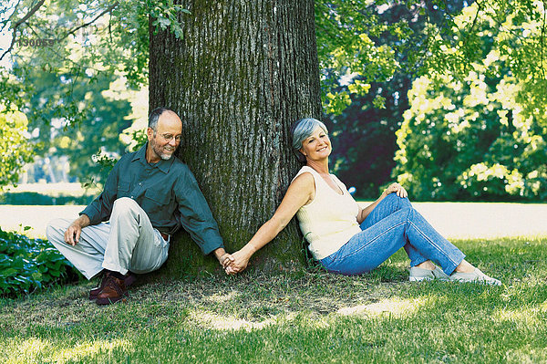 Paar sitzt unter einem Baum