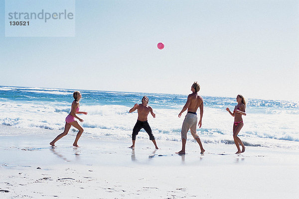 Gruppe von Freunden  die mit einem Ball am Strand spielen
