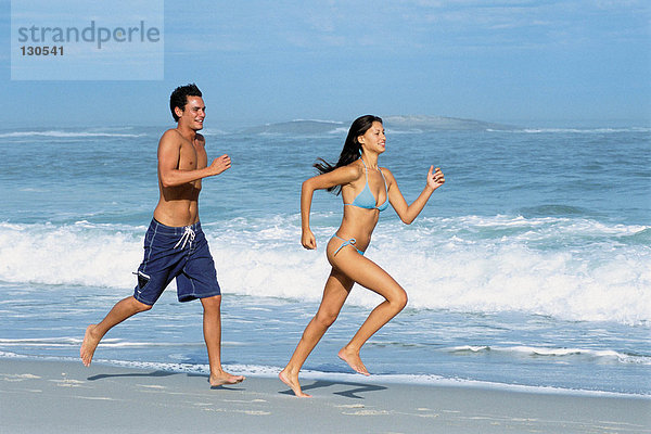 Frau und Mann joggen am Strand
