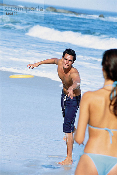 Mann und Frau beim Frisbee spielen am Strand