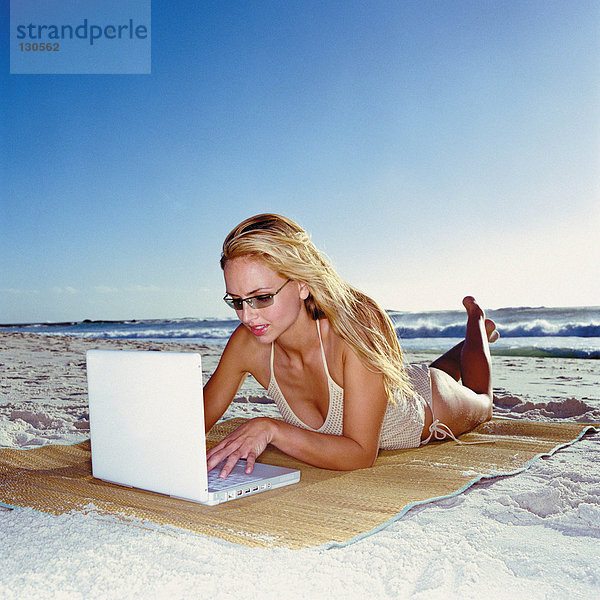 Frau mit Laptop am Strand