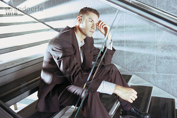 Geschäftsmann auf moderner Treppe sitzend