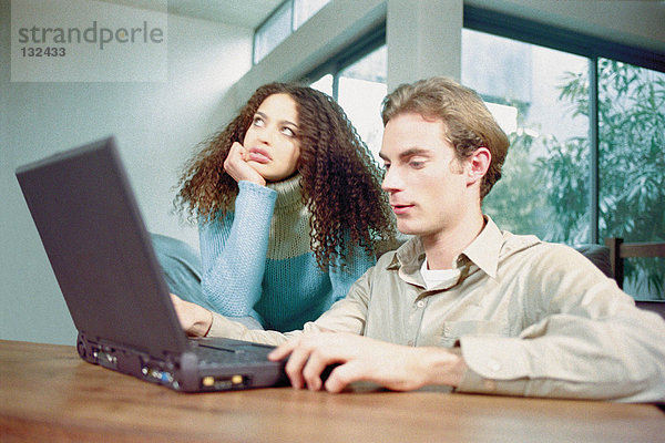 Mann und Frau zu Hause mit Laptop