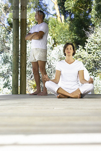 Frau beim Yoga draußen mit stehendem Mann