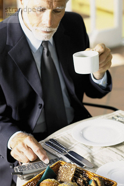 Geschäftsmann beim Frühstück mit dem Handy