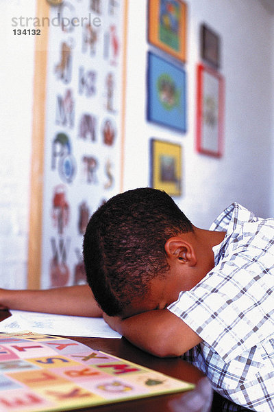 Junge schläft bei den Hausaufgaben