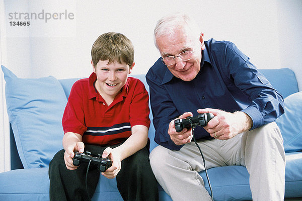 Großvater und Enkel spielen mit Computerspiel