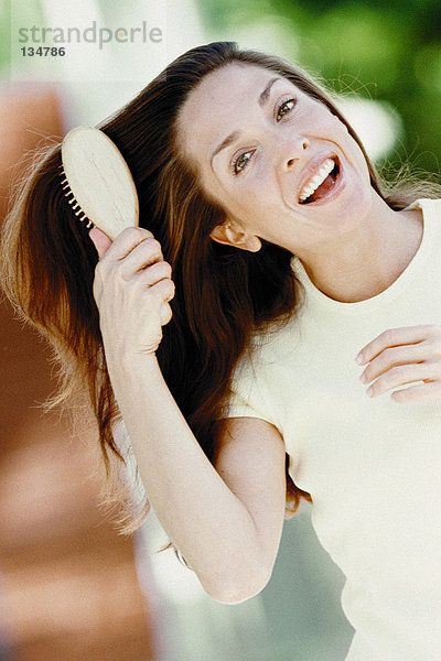 Frau bürstet Haare im Freien