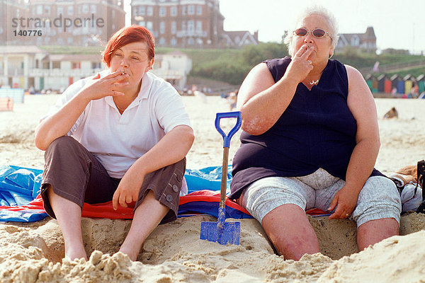 Zwei Frauen rauchen am Strand