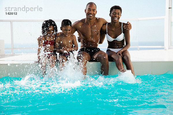 Familie sitzend am Pool