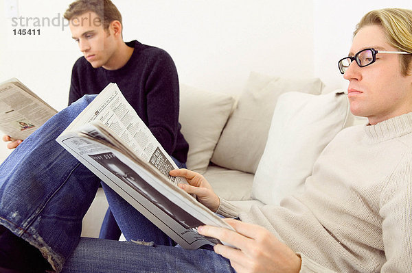 Männer beim Zeitungslesen auf dem Sofa