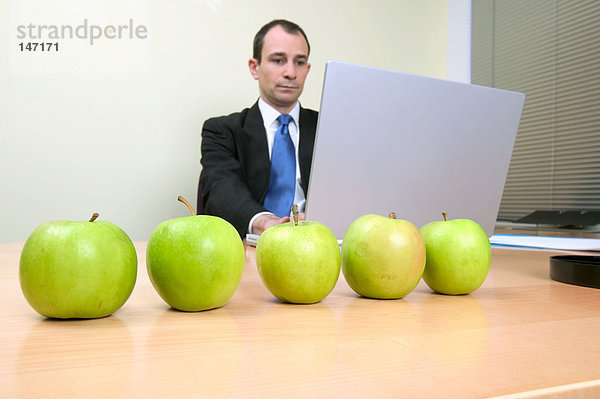 Geschäftsmann mit Äpfeln auf dem Schreibtisch