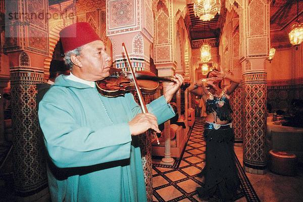 Seitenprofil des Mannes Geigenspiel mit Frau tanzen im Hintergrund  Hotel Mamounia  Marrakesch  Marokko