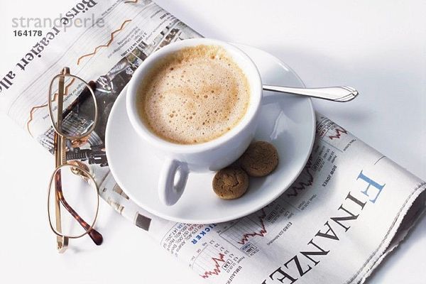Tasse Kaffee und Gläser auf Zeitungspapier