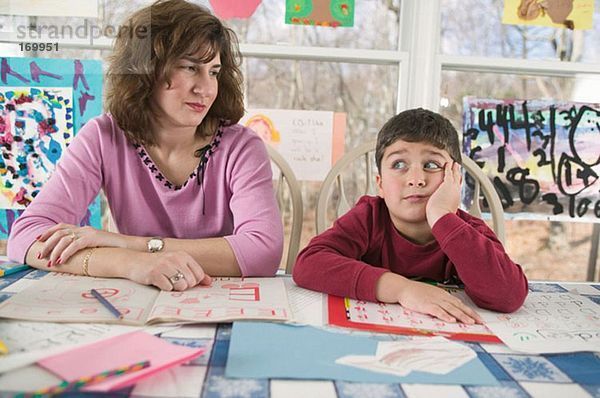 Mutter hilft gelangweiltem Sohn bei den Hausaufgaben