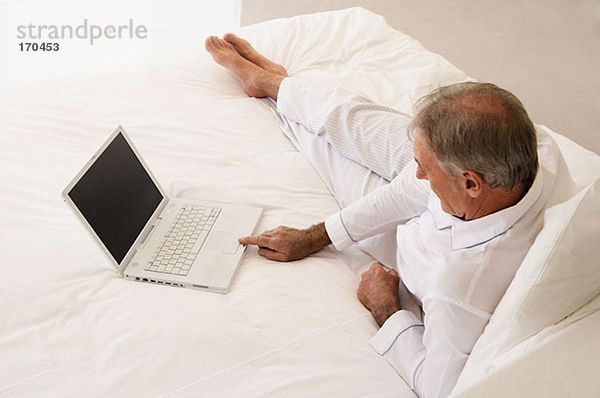 Mann mit Laptop im Bett