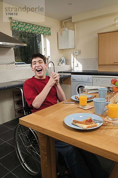 Behinderter Mann lacht am Frühstückstisch