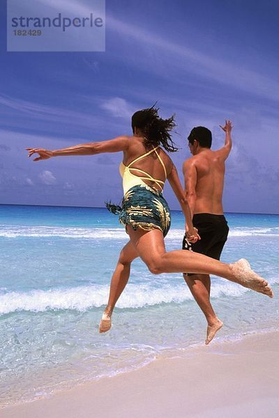 Paar springen am Strand