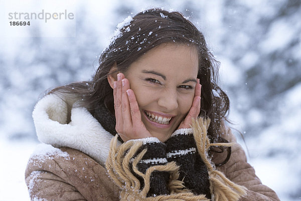 Frau im Schnee mit Händen im Gesicht