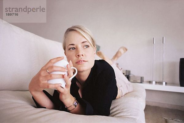 Frau entspannt auf dem Sofa bei einem Drink