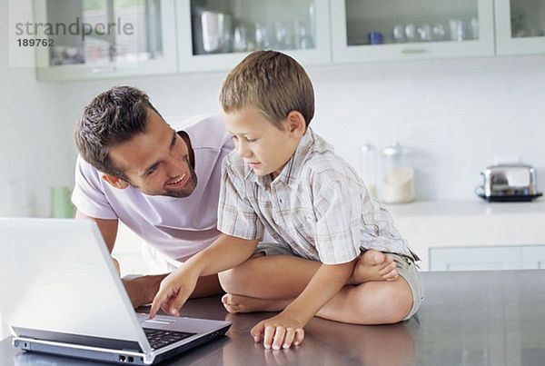 Vater zeigt Sohn  wie man einen Laptop benutzt