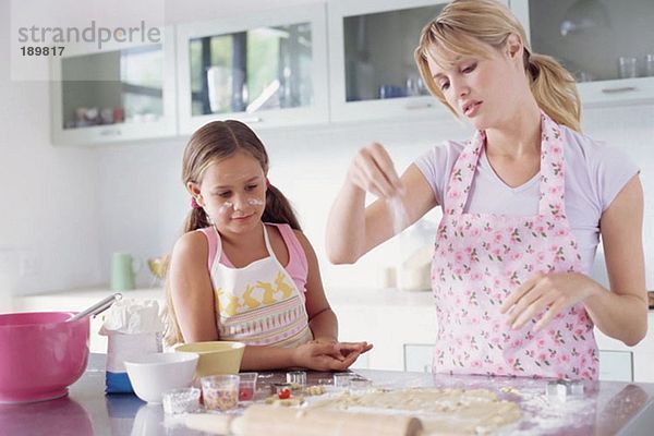 Mädchen hilft Mutter beim Kekse backen