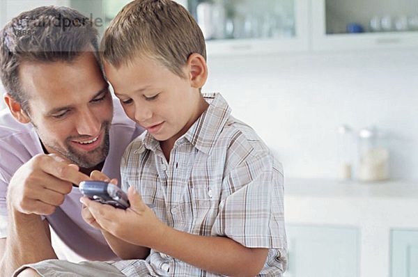 Vater zeigt dem Sohn  wie man das Handy benutzt.